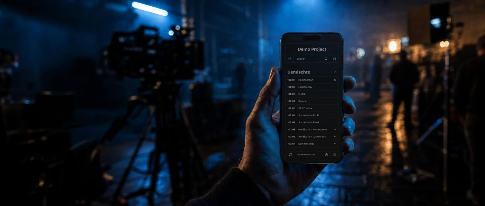 A prop master holds a picture phone showing the scene overview on set